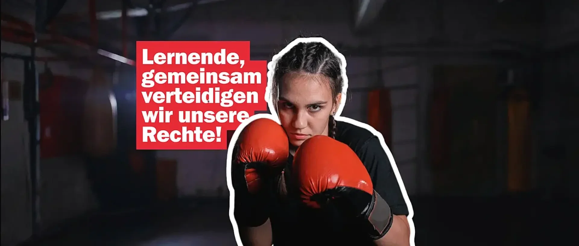 Eine Frau mit geflochtenen Haaren und roten Boxhandschuhen steht kampfbereit da. Der deutsche Text auf der linken Seite lautet: Lernende, gemeinsam verteidigen wir unsere Rechte! Im Hintergrund ist eine schwach beleuchtete Sporthalle zu sehen.